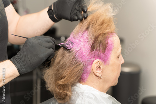 an elderly woman in a beauty salon dyes her hair