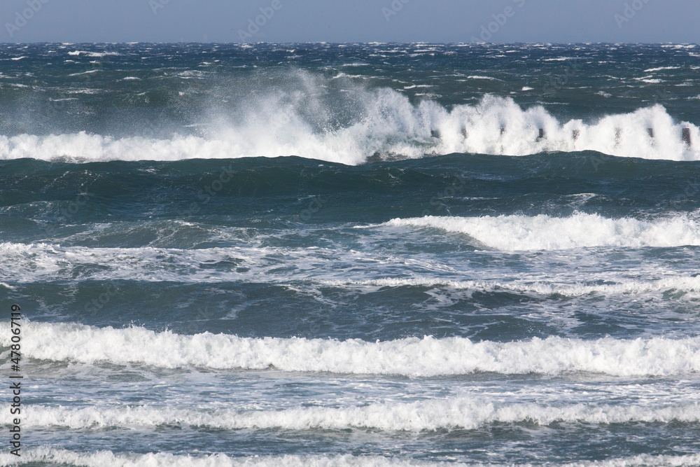 冬の海、沖の杭に当たって砕ける波の形の面白さ。