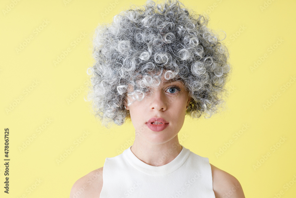 Beautiful young woman in wig standing in studio