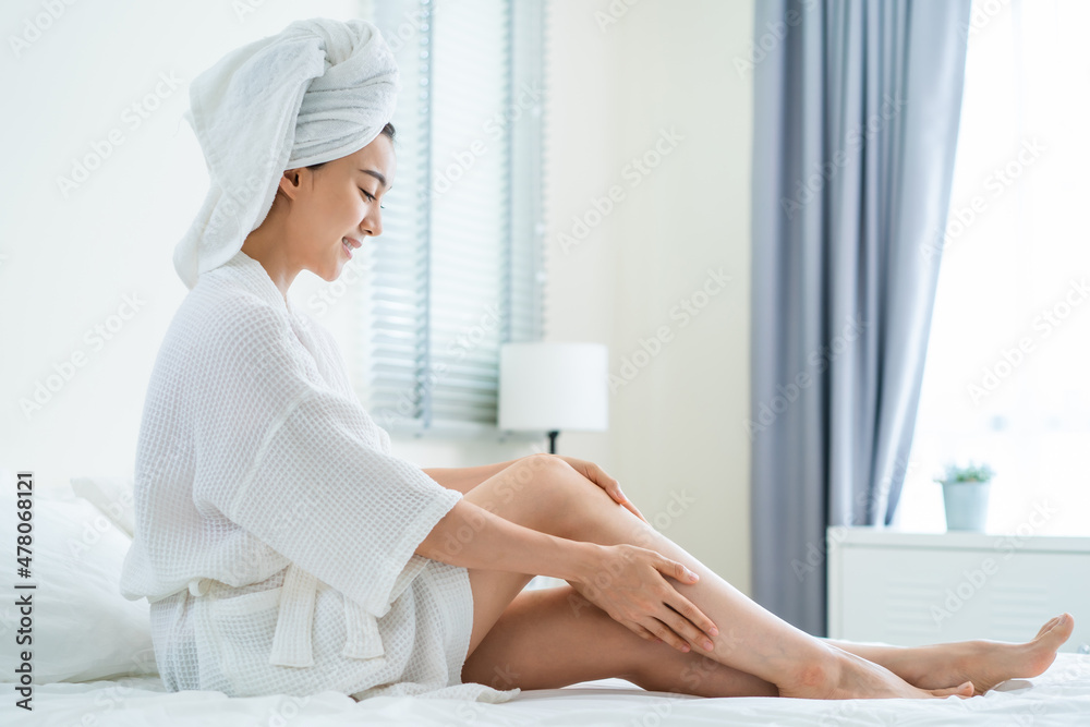 Asian beautiful woman put smooth and soft skin care on legs in bedroom Asian beautiful woman put smooth and soft skin care on legs in bedroom