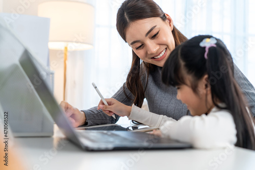 Asian little young girl kid learning online class at home with mother. 