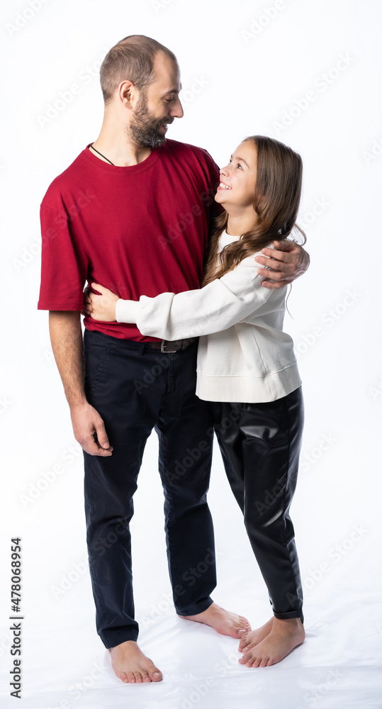 dad hugs daughter by the shoulders in the studio. a man in a burgundy-red T-shirt, a girl in a white sweatshirt. isolated white background dad hugs daughter by the shoulders in the studio. a man in a burgundy-red T-shirt, a girl in a white sweatshirt. isolated white background
