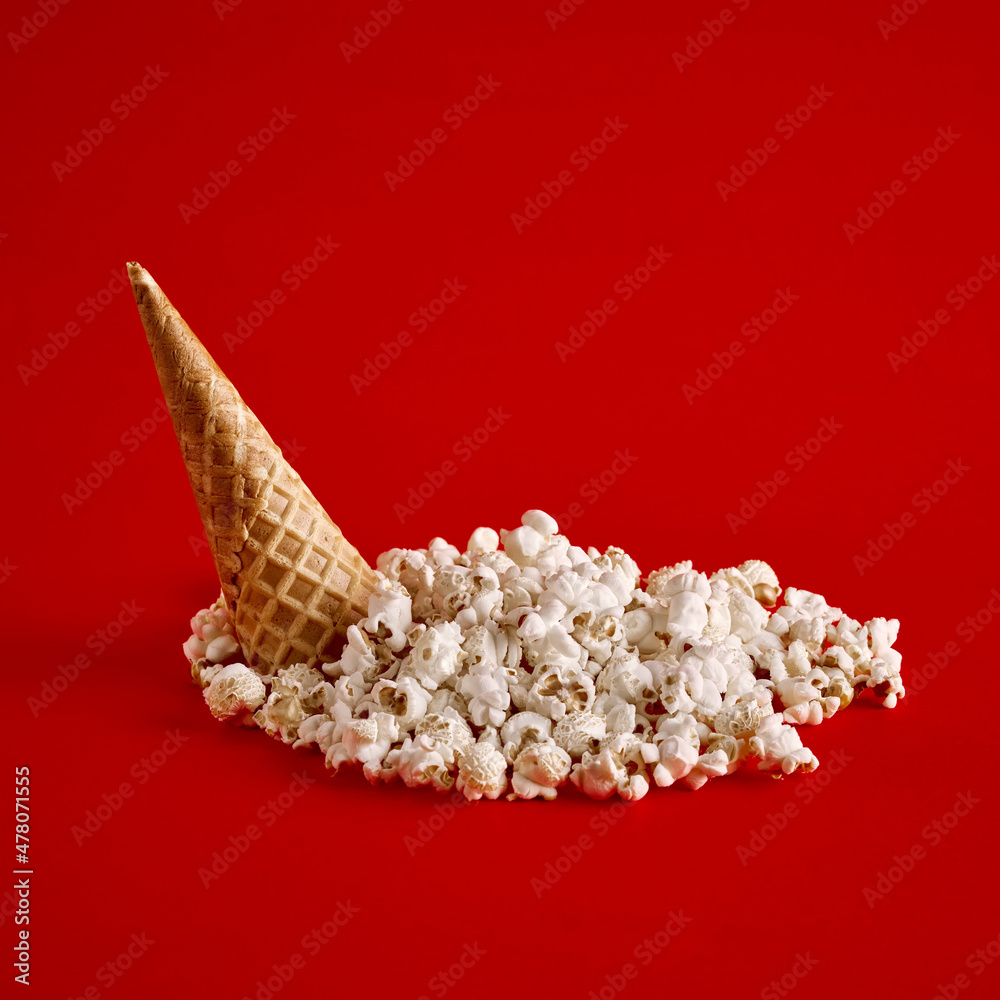 Upside down ice cream cone with spilled popcorn on red background. Upside down ice cream cone with spilled popcorn on red background.