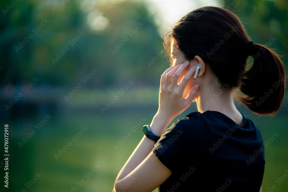 Asian woman wearing a black dress  talking phone in the park