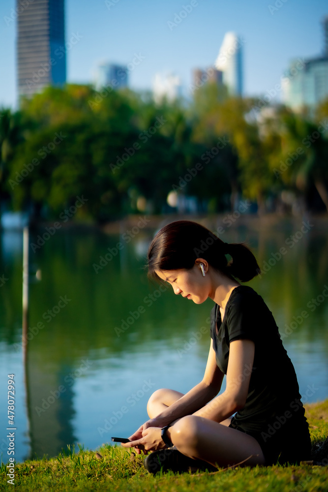 Asian woman waring a black dress sitting after jogging in the park