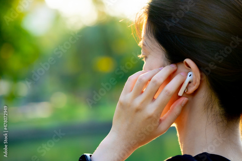 Asian woman wearing a black dress talking phone in the park