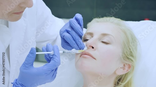 Senior woman cosmetologist making injections of botulotoxin in face of young woman. High quality 4k footage photo