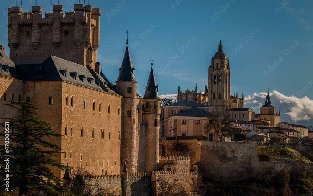 City skyline of Segovia, Spain, with castle and cathedral, against blue sky
