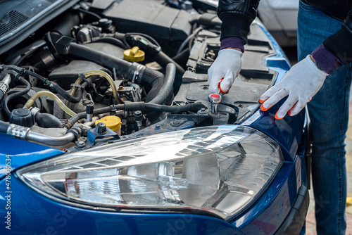 Male hands with a wrench  repair to engine in the open hood of the car © RomanR