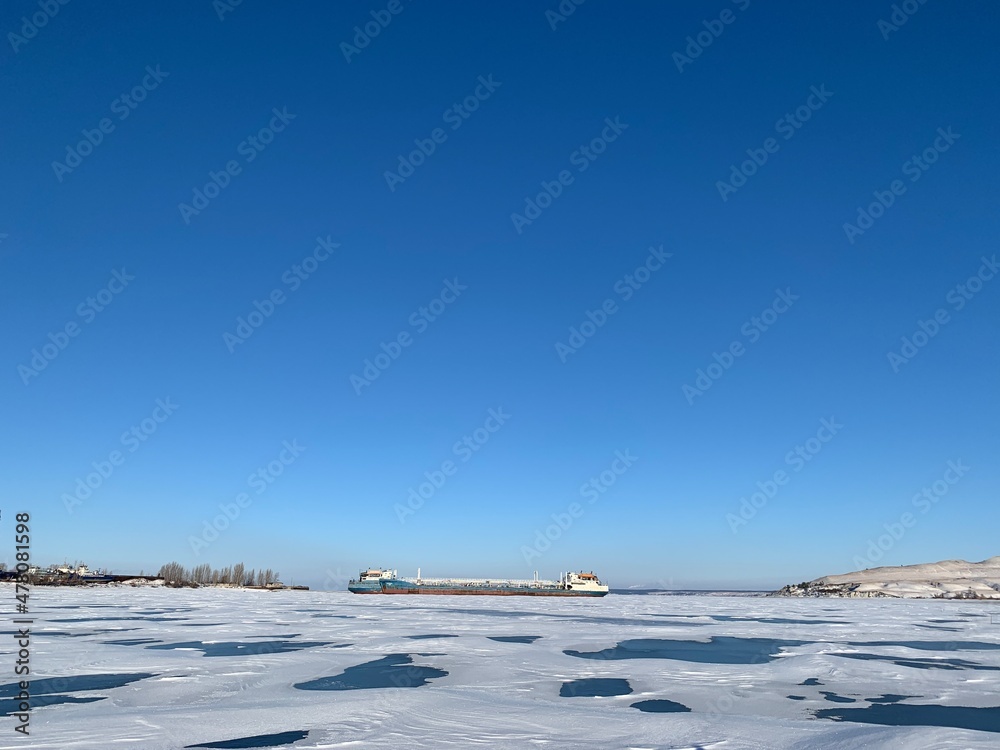 Obraz premium a view of the ships in the winter anchorage on the Volga River in ice and covered with snow