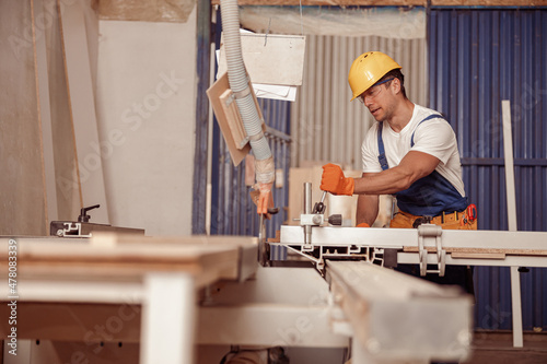 Handsome man carpenter using woodworking machine in workshop © Friends Stock