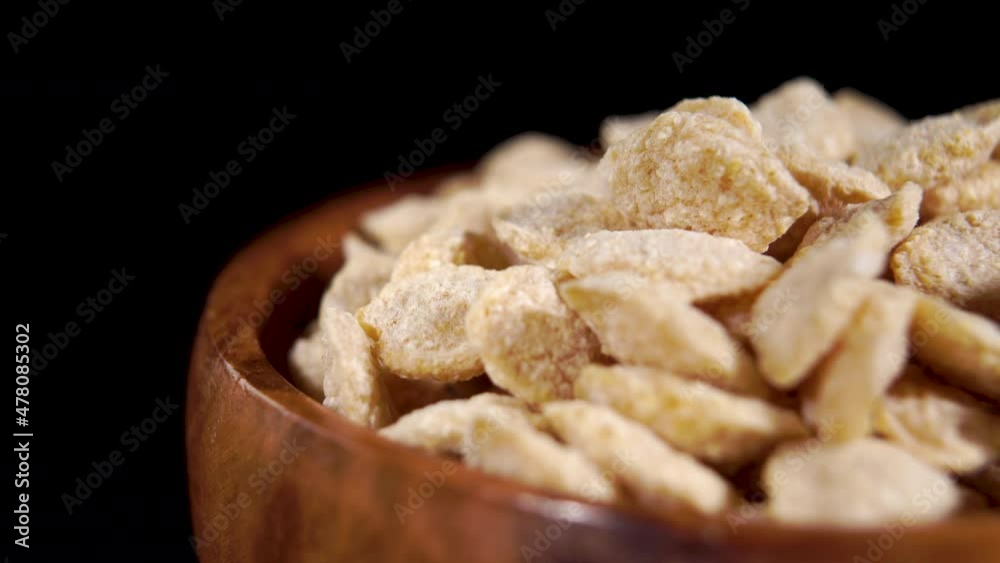 Crunchy dry quinoa flakes in rustic wood bowl. Healthy breakfast concept. Macro. Rotation. On black background Crunchy dry quinoa flakes in rustic wood bowl. Healthy breakfast concept. Macro. Rotation. On black background