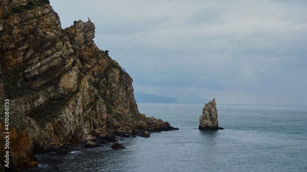 A lonely rock in the sea on the background of the Crimean mountains.