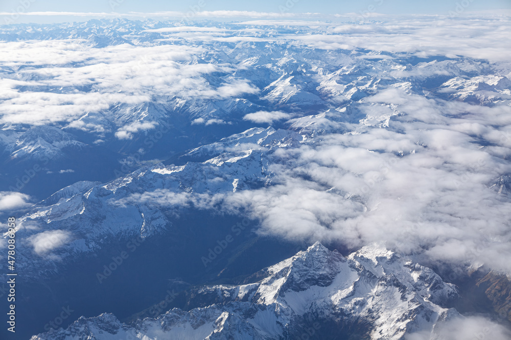 Clouds and snowy peaks . Aerial view of mountains in the winter 
