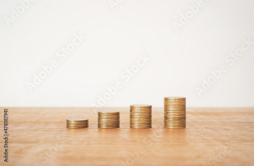 stacks of gold money coin on wooden desk and white background with copy space. Saving money concept. 