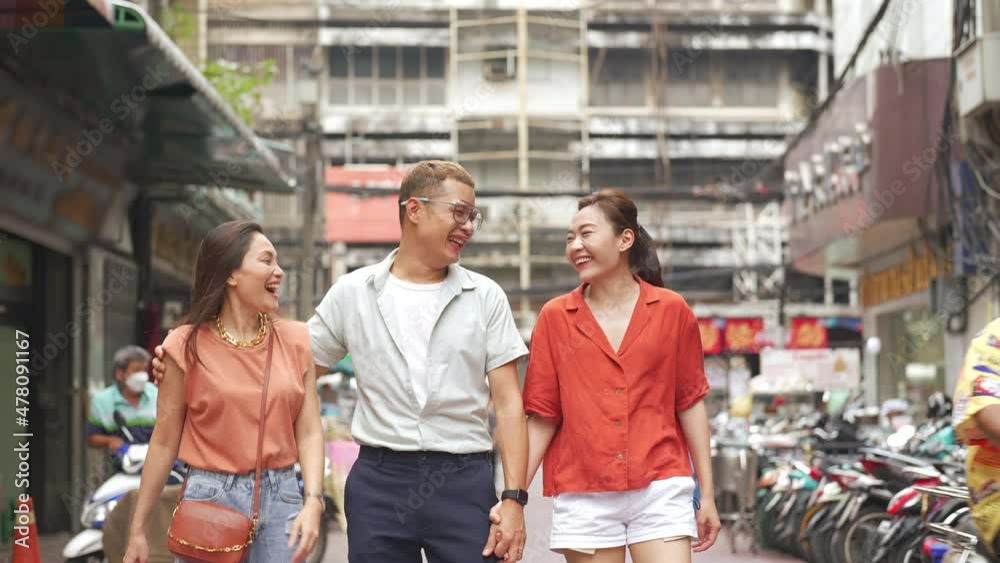 Group of Asian people friends tourist walking and shopping together at Chinatown in Bangkok city, Thailand. Male and female friend enjoy and having fun outdoor lifestyle travel and eating street food.