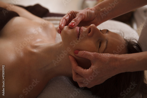 Close up of a middle aged woman getting anti-wrinkle face massage at spa by professional beautician
