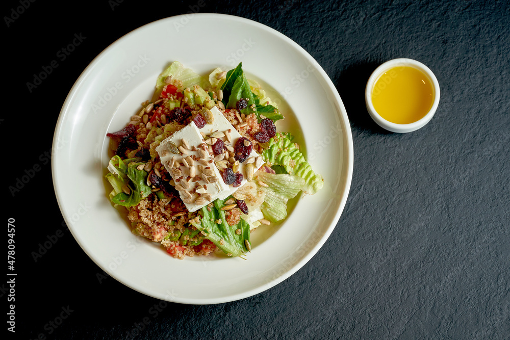Quinoa and feta salad in white plate on black background