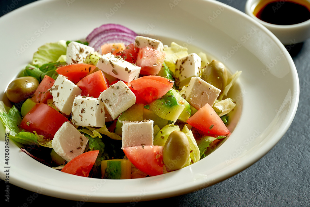 Salad with olives, tomatoes and feta in a white plate. Greek salad