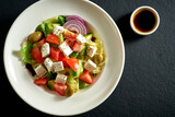 Salad with olives, tomatoes and feta in a white plate. Greek salad