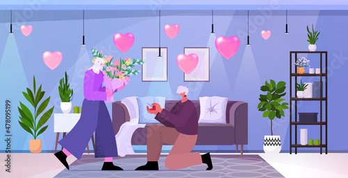 senior man kneeling holding engagement ring proposing aged woman marry him happy valentines day concept living