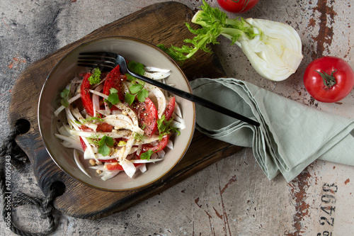 a bowl of salad with fennel and tomatoes on the table