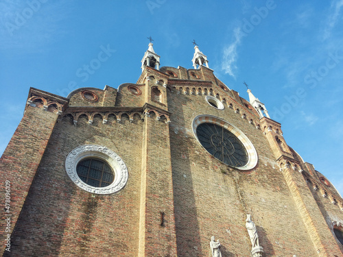 Red-brick façade of the Basilica of Santa Maria Gloriosa dei Frari, built in 13th-14th century, with rose windows and sculptures, in the San Polo district of Venice, Italy,  photo
