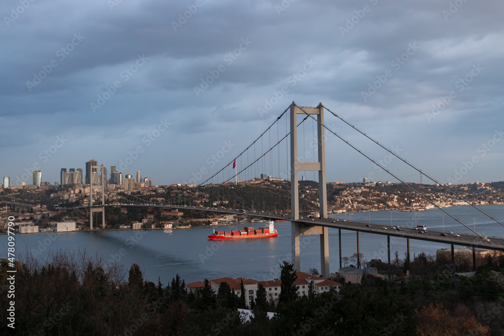 Fototapeta premium A very beautiful Istanbul bosphorus and bridge view in sunrise. A trade ship under the bridge. Morning light.