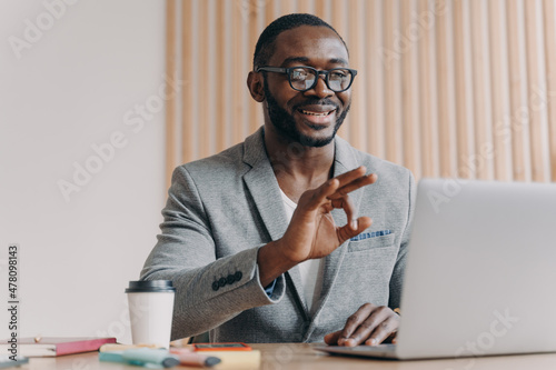 Young positive sitisfied african american businessman in suit talking with business partner online photo