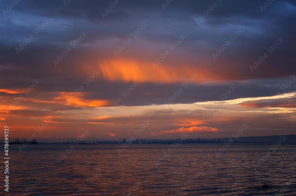 Calm sea with sunset sky and sun through the clouds over. Meditation ocean and sky background. Tranquil seascape. Colorful horizon over the water.