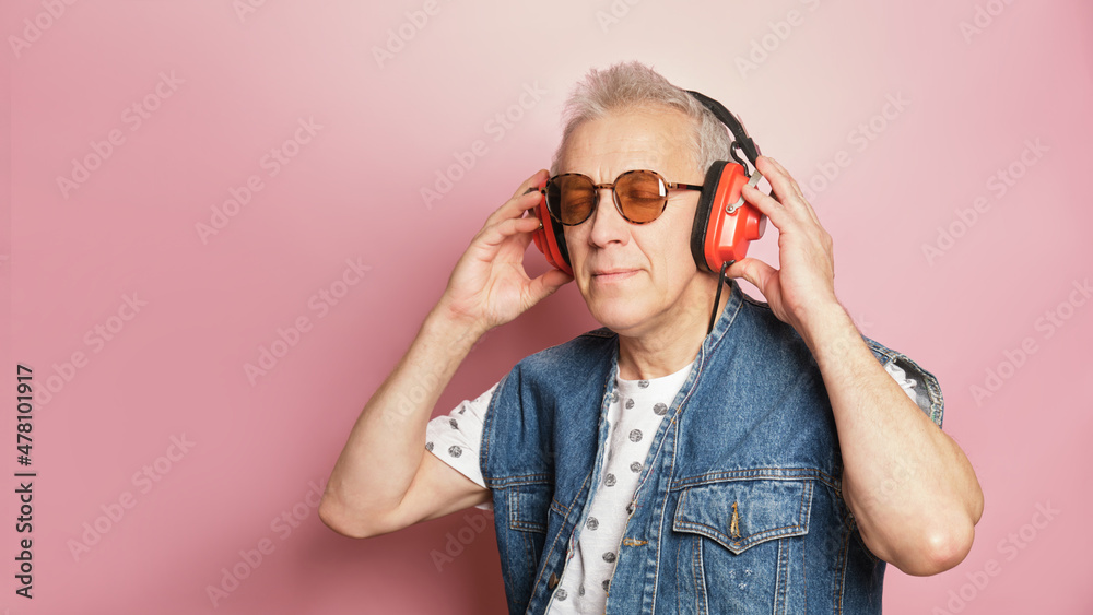 funny gray-haired elderly pensioner man in sunglasses, retro headphones and denim vest with 90s style funny gray-haired elderly pensioner man in sunglasses, retro headphones and denim vest with 90s style