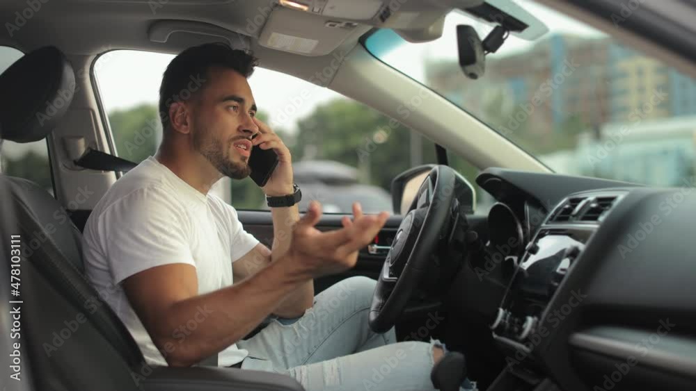 A man is sitting in the driver's seat. He is talking emotionally on the phone and counting on his fingers. 4K 50fps A man is sitting in the driver's seat. He is talking emotionally on the phone and counting on his fingers. 4K 50fps