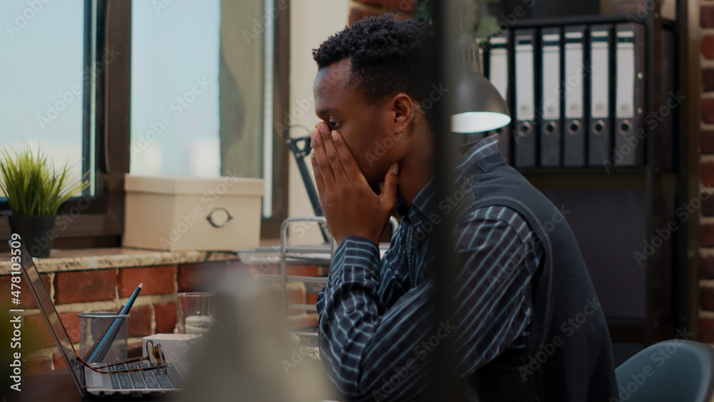 Fototapeta premium Anxious worker finging put bad news about business project in office. Company accountant worrying about work failure, planning financial report under pressure on laptop. Frustrated man
