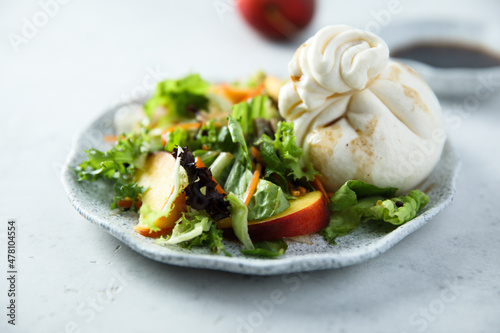 Healthy green salad with peach and burrata cheese
