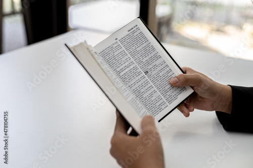 A person is reading the Bible, he is praying to the Bible, he is reading and studying the Bible. Concept of Christianity and Bible Study.
