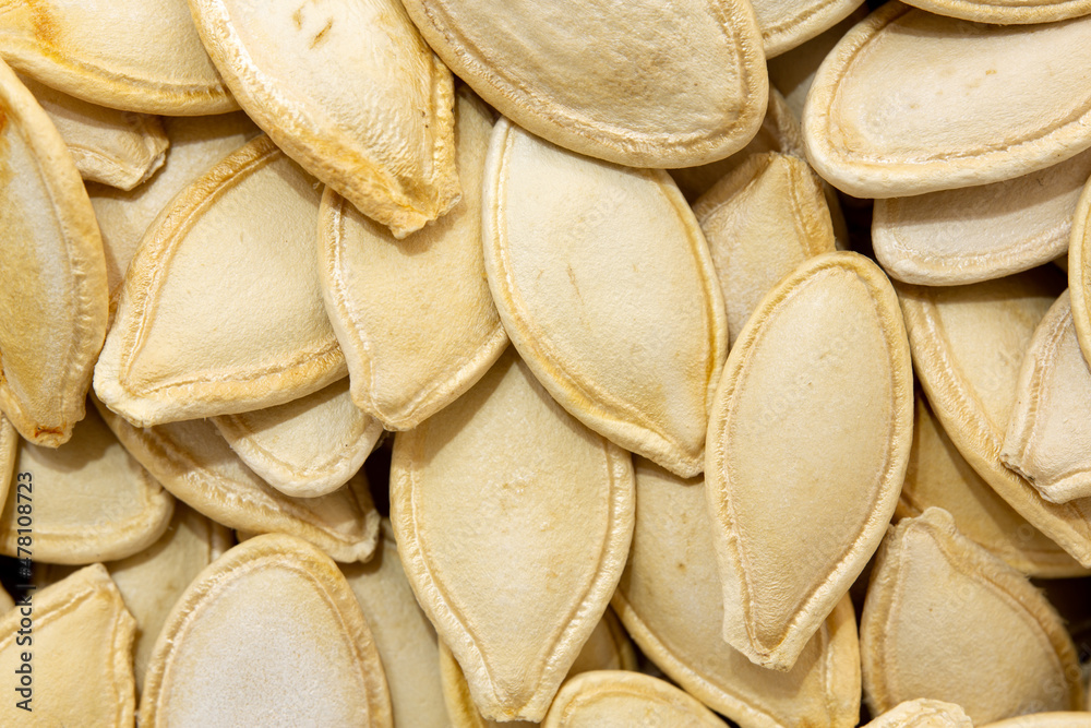Background photo of pumpkin seed grains. Macro view of roasted pumpkin seeds. Shelled pumpkin seeds in the middle in selective focus.