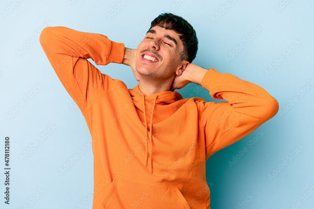 Young mixed race man isolated on blue background stretching arms, relaxed position. Young mixed race man isolated on blue background stretching arms, relaxed position.