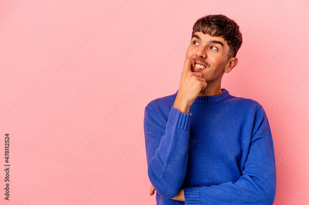 Young mixed race man isolated on pink background relaxed thinking about something looking at a copy space. Young mixed race man isolated on pink background relaxed thinking about something looking at a copy space.