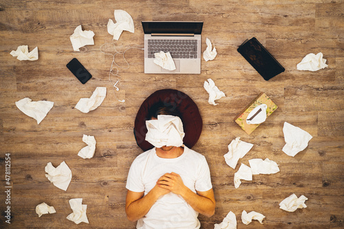 Young Man with laptop and handkerchief on his face lie on floor