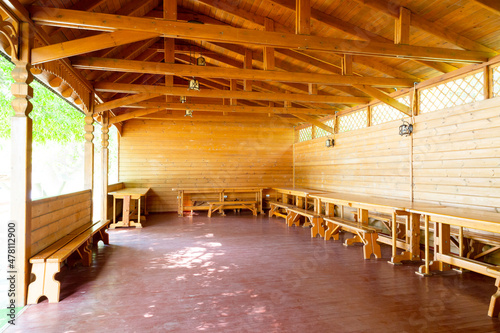 Wooden gazebo interior with benches and tables