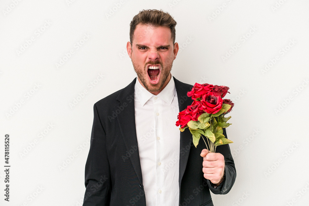 Young caucasian man holding bouquet of flowers isolated on white background screaming very angry and aggressive. Young caucasian man holding bouquet of flowers isolated on white background screaming very angry and aggressive.