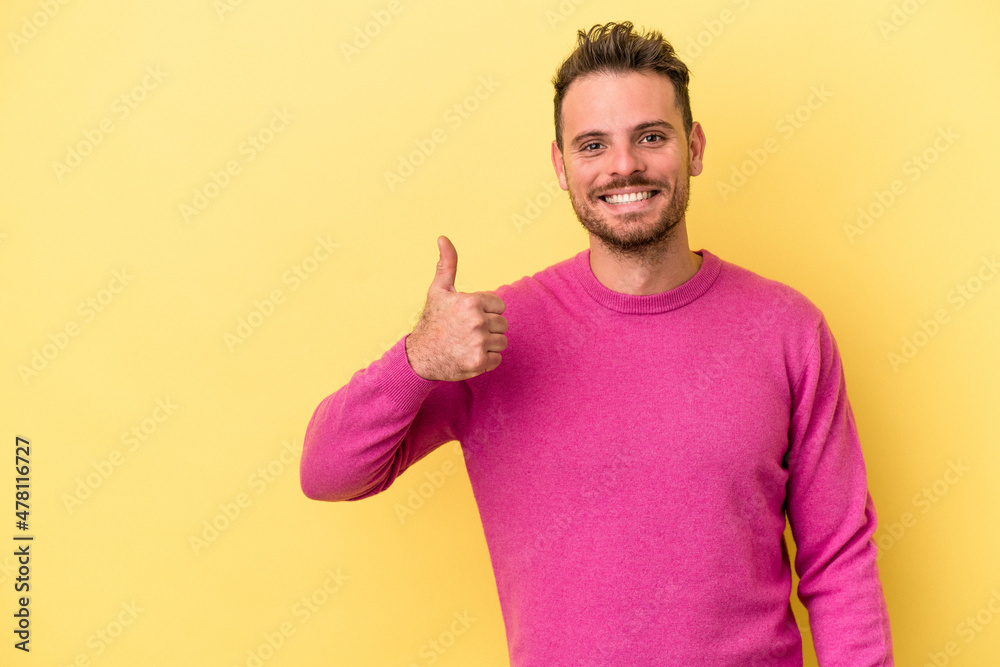 Young caucasian man isolated on yellow background smiling and raising thumb up Young caucasian man isolated on yellow background smiling and raising thumb up