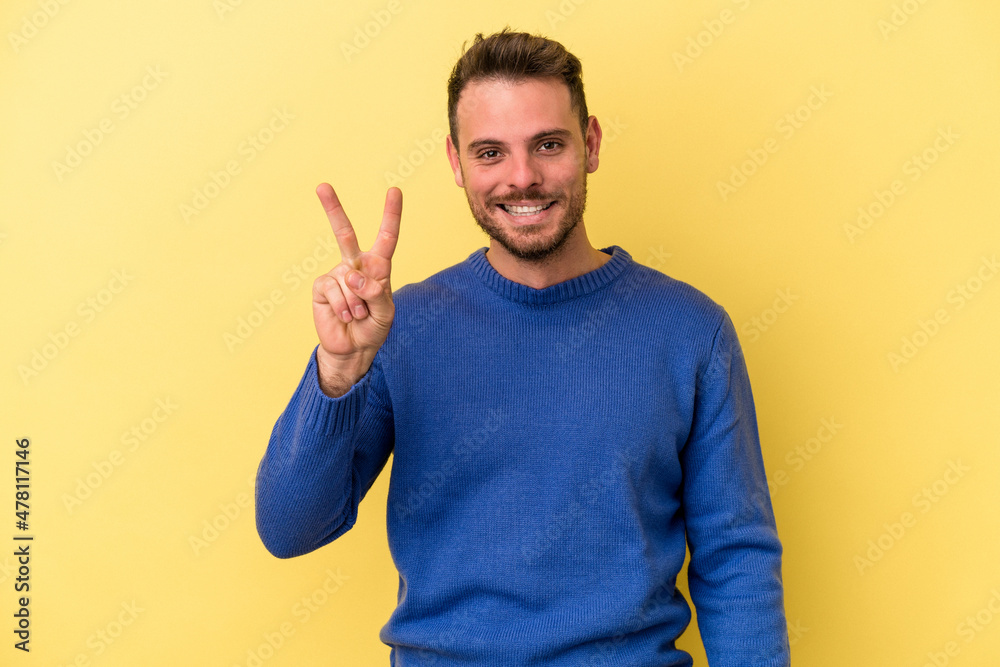 Young caucasian man isolated on yellow background showing number two with fingers. Young caucasian man isolated on yellow background showing number two with fingers.