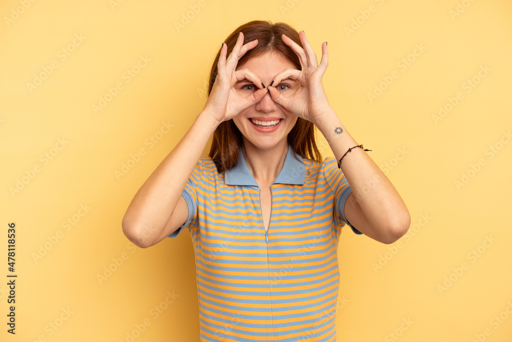 Young English woman isolated on yellow background excited keeping ok gesture on eye. Young English woman isolated on yellow background excited keeping ok gesture on eye.