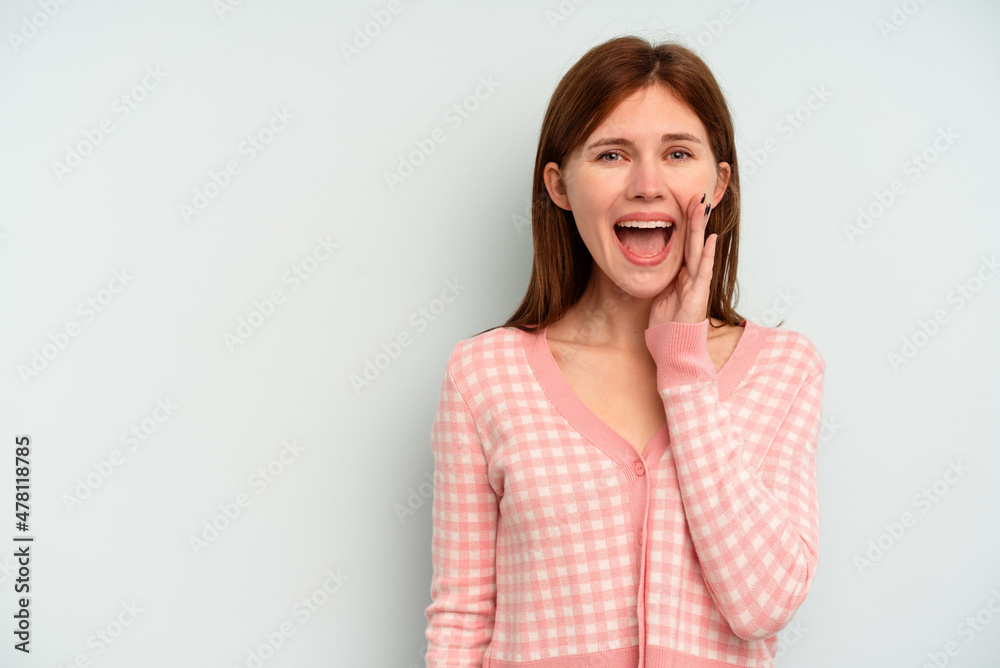 Young English woman isolated on blue background shouts loud, keeps eyes opened and hands tense. Young English woman isolated on blue background shouts loud, keeps eyes opened and hands tense.