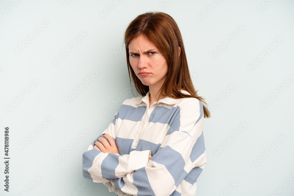 Young English woman isolated on blue background frowning face in displeasure, keeps arms folded. Young English woman isolated on blue background frowning face in displeasure, keeps arms folded.