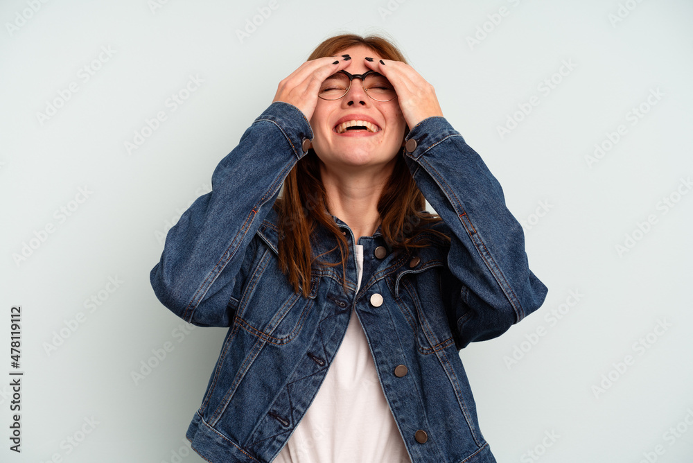 Young English woman isolated on blue background laughs joyfully keeping hands on head. Happiness concept. Young English woman isolated on blue background laughs joyfully keeping hands on head. Happiness concept.