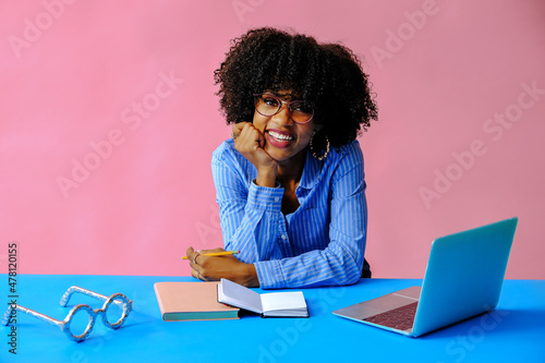 cheerful young african american black entrepreneur student businesswoman leaning on hand and smiling at camera at workplace
