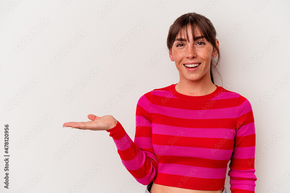 Young Argentinian woman isolated on white background showing a copy space on a palm and holding another hand on waist. Young Argentinian woman isolated on white background showing a copy space on a palm and holding another hand on waist.