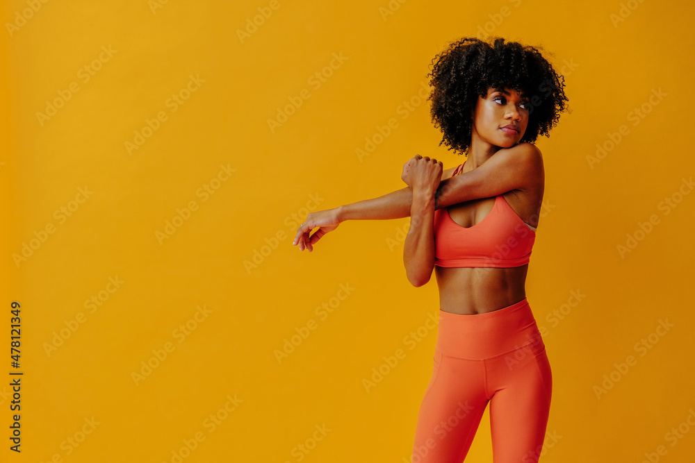 young fit black woman in sportswear posing isolated on yellow background - obrazy, fototapety, plakaty 